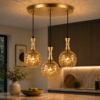 Suspension triple dorée installée dans une cuisine moderne avec lumière chaude