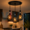 Suspension triple noire grillagée installée dans une cuisine moderne avec lumière chaude