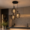 Suspension triple noire installée dans une cuisine moderne avec lumière chaude