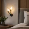 Applique murale LED design feuille noir et or installée dans une chambre moderne