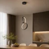 Suspension LED double anneau noire installée dans une salle à manger moderne