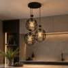 Suspension triple noire installée dans une cuisine moderne avec lumière chaude